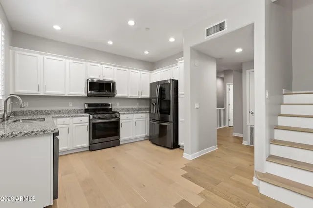 a view of an empty room with window and a kitchen