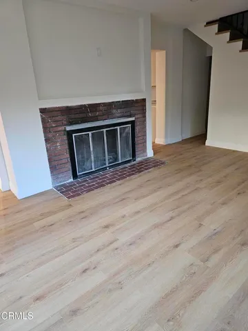 a view of empty room with wooden floor and fireplace