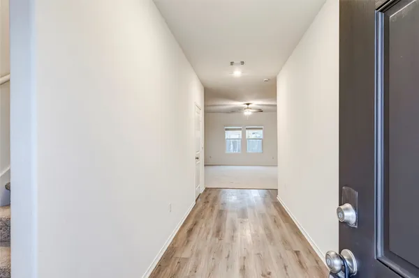 a view of a hallway with wooden floor and a bathroom