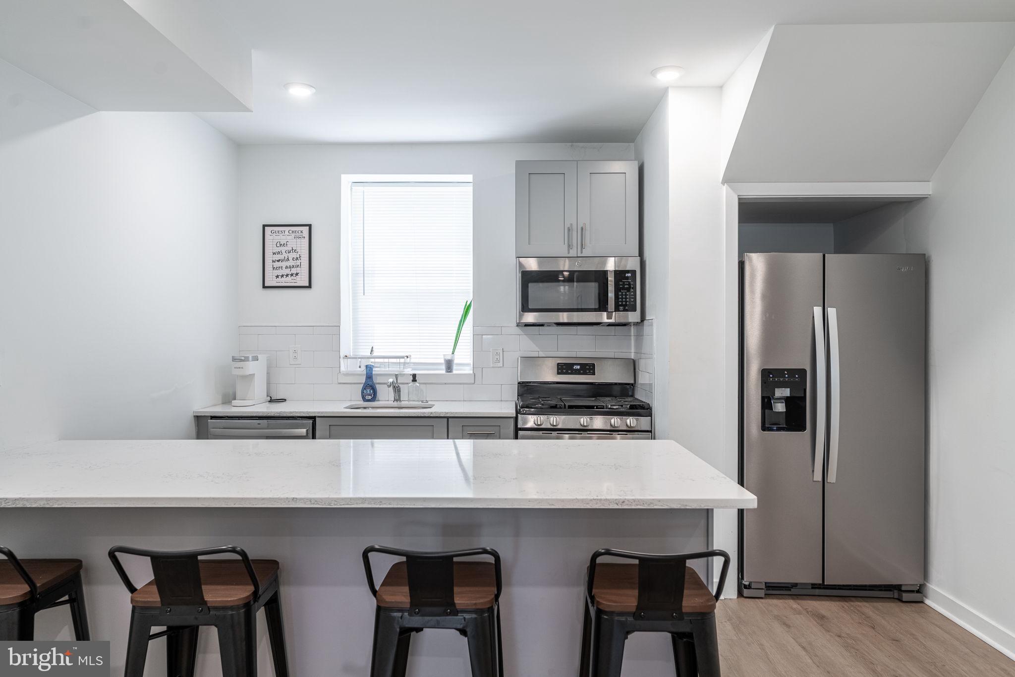 1105 South 27th Street Philadelphia, PA 19146 - Photo 3 of 19 a kitchen with stainless steel appliances a table chairs refrigerator and sink