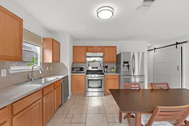 a kitchen with stainless steel appliances granite countertop a sink dishwasher stove and refrigerator