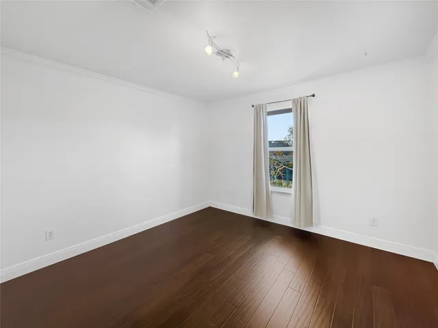 an empty room with wooden floor and window