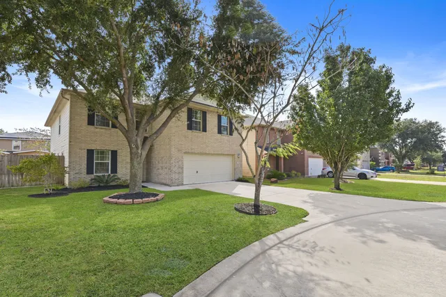 a front view of a house with garden and trees
