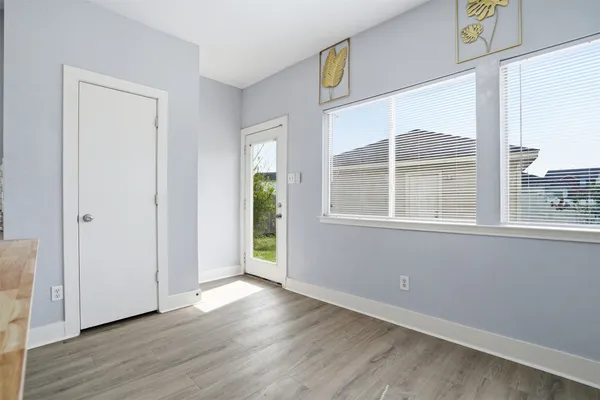 an empty room with wooden floor and windows