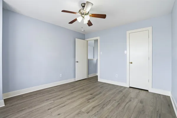 an empty room with wooden floor chandelier fan and closet area