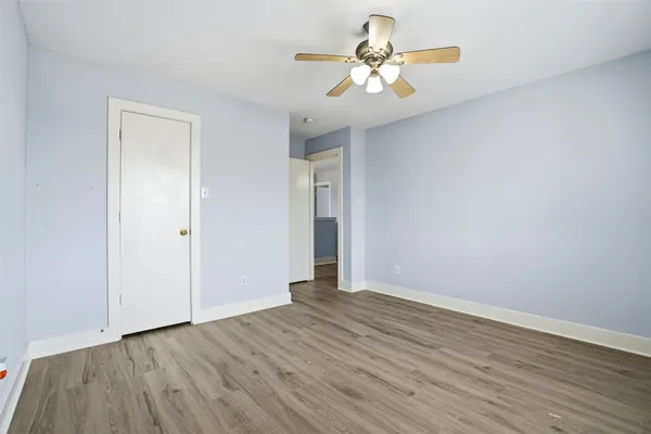 an empty room with wooden floor and ceiling fan