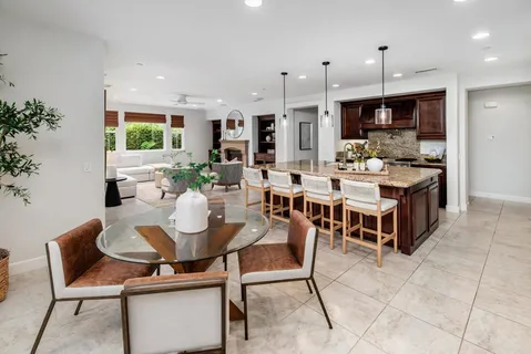 a kitchen with stainless steel appliances granite countertop a stove a sink a microwave a dining table and chairs with the view of living room