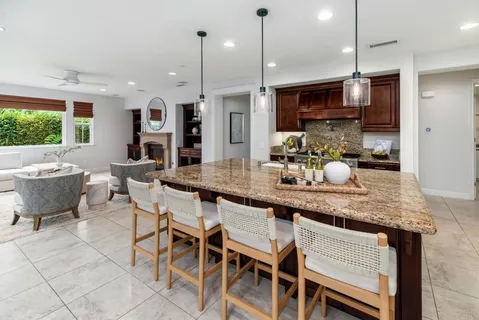 a kitchen with granite countertop kitchen island stainless steel appliances and wooden cabinets