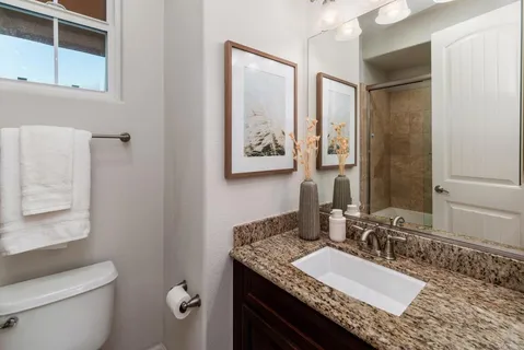 a bathroom with a granite countertop double vanity sink toilet and shower