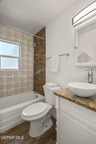 a bathroom with a granite countertop toilet a sink and a mirror