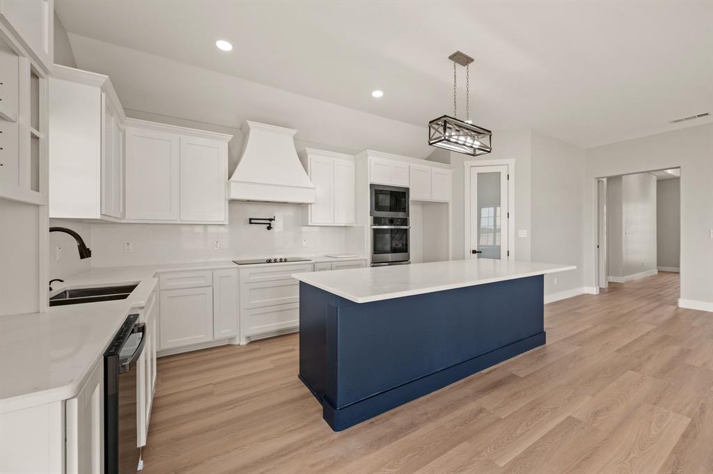 806 N Avenue East Springtown, TX 76082 - Photo 6 of 25 a kitchen with wooden floors and white cabinets