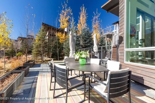 a view of a patio with a dining table and chairs with wooden floor and fence