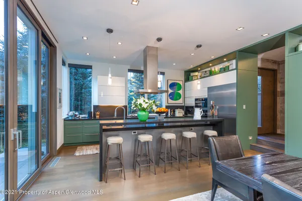 a dining area with stainless steel appliances kitchen island granite countertop a table chairs and a living room view