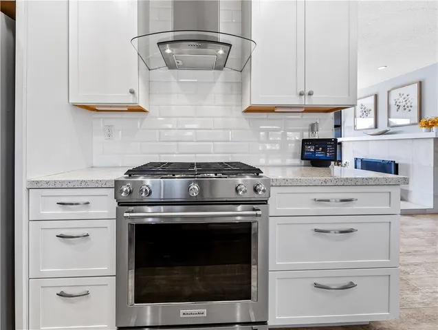 a kitchen with stainless steel appliances granite countertop a stove and a wooden floors