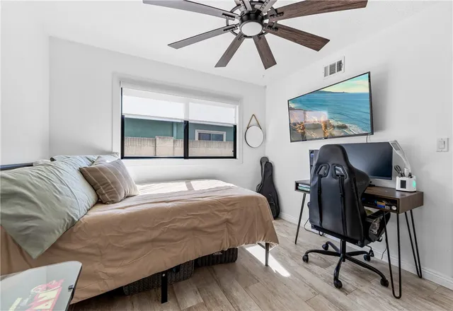 a bedroom with a bed and a large window with wooden floor
