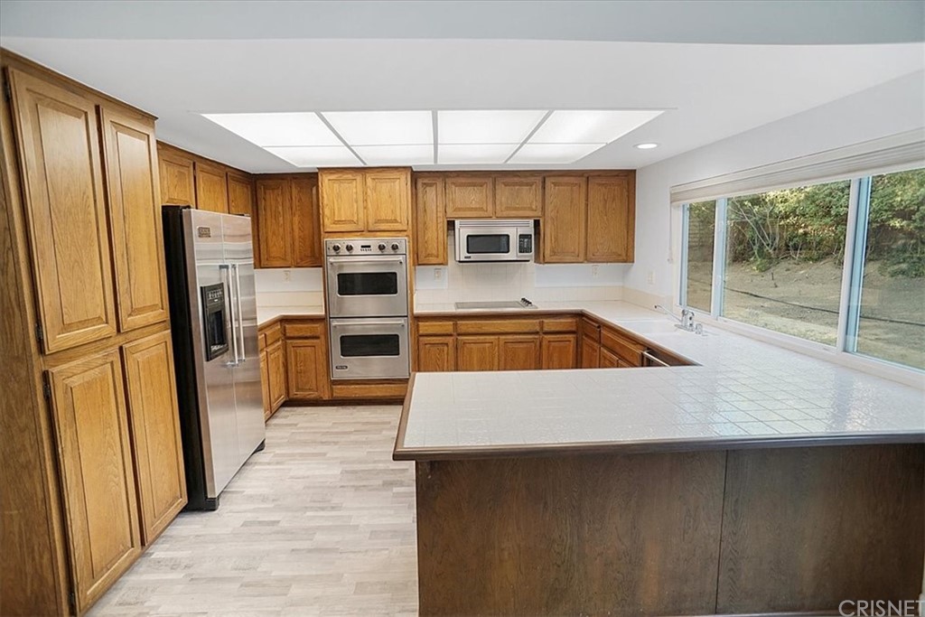 12230 Stewarton Drive Porter Ranch, CA 91326 - Photo 8 of 25 a kitchen with a refrigerator a sink and a stove top oven