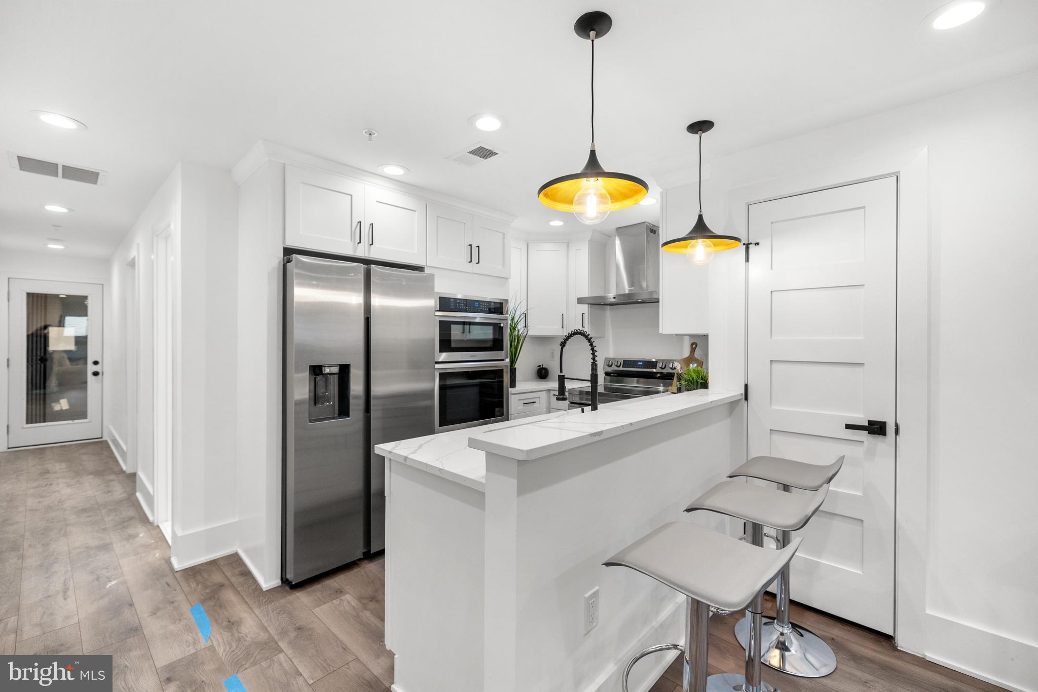 113 18th Street Southeast, Unit 1 Washington, DC 20003 - Photo 5 of 37 a kitchen with stainless steel appliances kitchen island a table chairs in it and wooden floors
