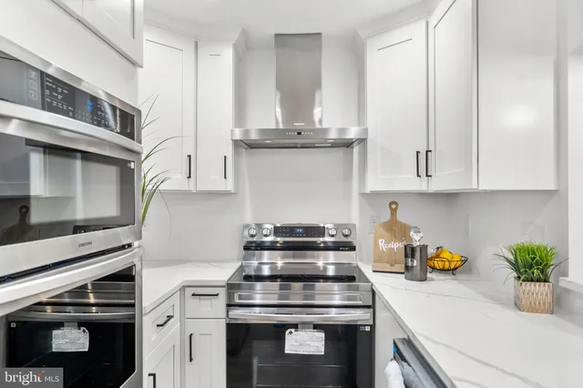 a kitchen with stainless steel appliances granite countertop a stove a white cabinets and a granite counter tops
