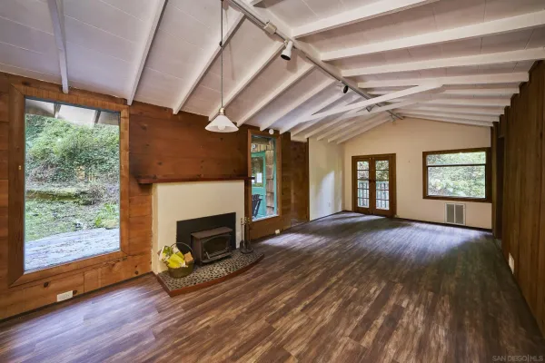 a view of an empty room with wooden floor fireplace and a window