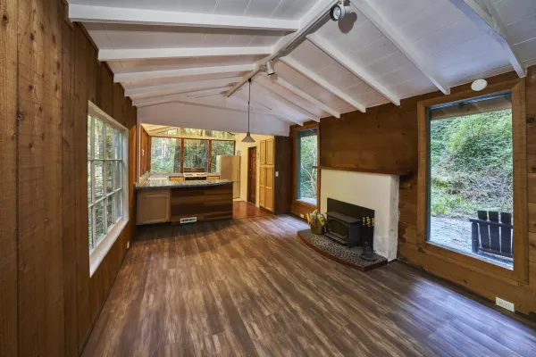 a view of a room with wooden floor fireplace and windows