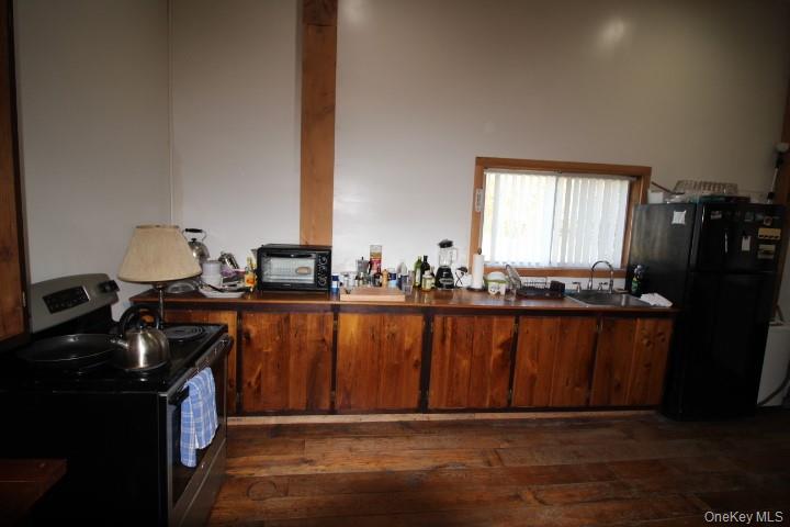 13 Creamery Road Livingston Manor, NY 12758 - Photo 23 of 23 Kitchen with stainless steel electric stove, freestanding refrigerator, dark wood-type flooring, brown cabinets, and dark countertops