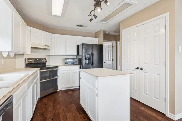 a kitchen with a sink a stove top oven and white stainless steel appliances