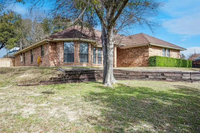 a backyard of a house with table and chairs under an umbrella