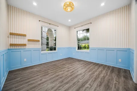 a view of an empty room with window and wooden floor