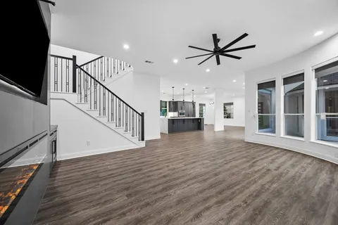 a view of a livingroom with wooden floor a ceiling fan and windows