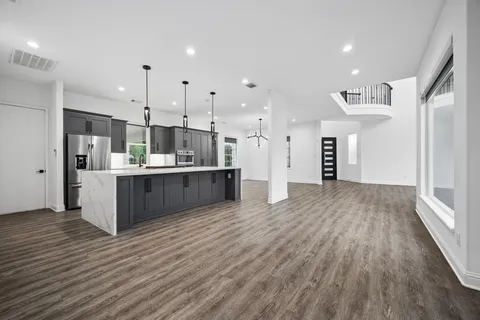 a large kitchen with stainless steel appliances kitchen island a large counter top and a wooden floors