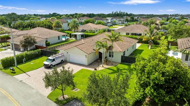 an aerial view of residential houses with outdoor space and trees