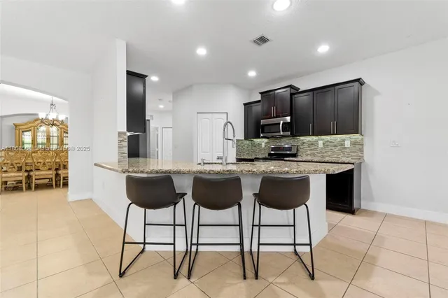 a kitchen with kitchen island granite countertop a counter top space appliances and a dining table