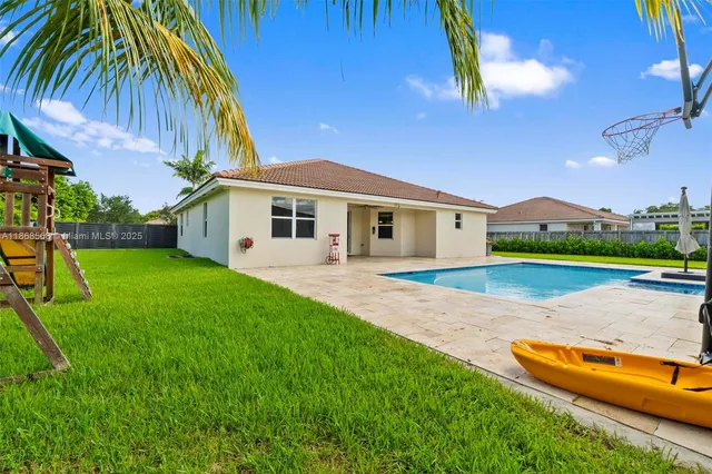 a view of house with backyard and swimming pool