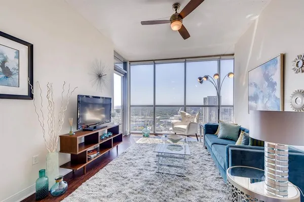 a living room with furniture a flat screen tv and a floor to ceiling window