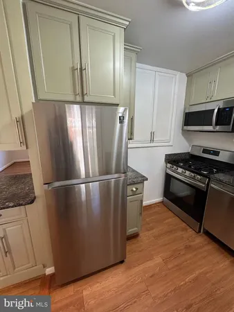 a kitchen with stainless steel appliances granite countertop a refrigerator a stove and a sink with wooden floor