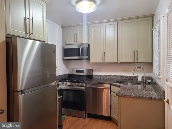 a kitchen with stainless steel appliances granite countertop a refrigerator a stove a sink and a microwave