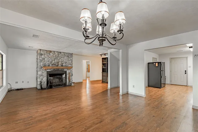 a view of an empty room with wooden floor fireplace and a window