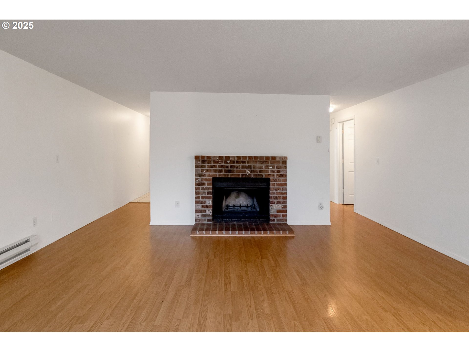 8524 Southwest Mohawk Street Tualatin, OR 97062 - Photo 5 of 30 a view of an empty room with wooden floor fireplace and a window