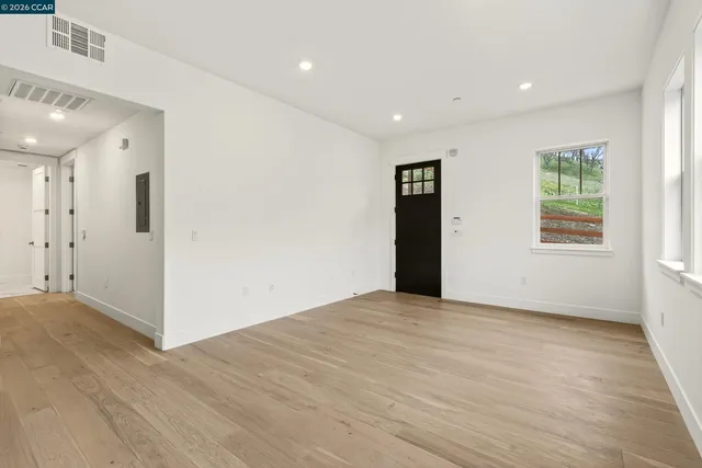 a view of an empty room with wooden floor and a window