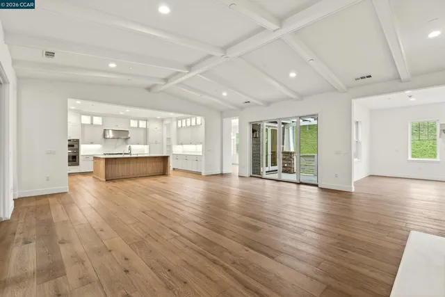 a view of empty room with kitchen and window