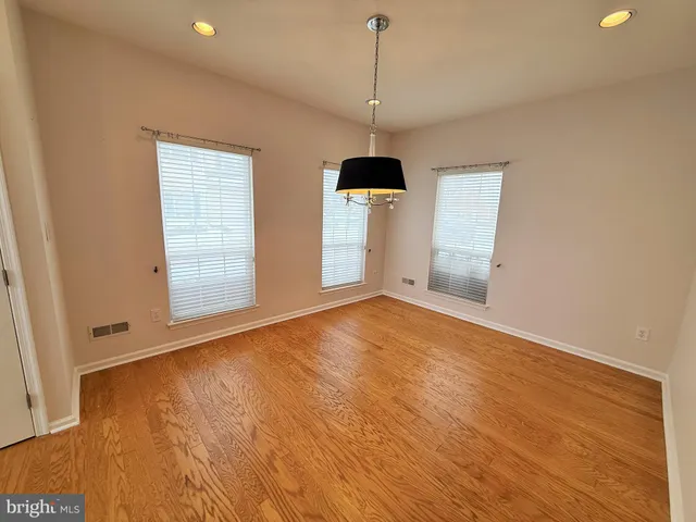 a view of empty room with wooden floor and ceiling fan