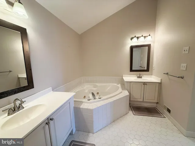 a bathroom with a tub a sink and mirror