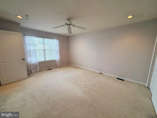 an empty room with chandelier fan and windows