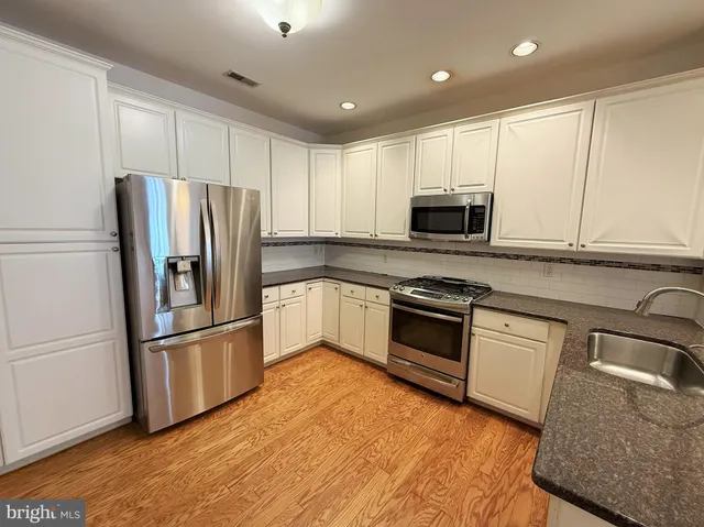 a kitchen with granite countertop a refrigerator stove and microwave