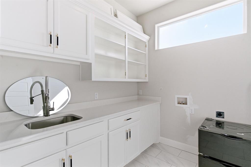 4600 Old Brock Road Weatherford, TX 76087 - Photo 18 of 37 Bright utility room featuring white cabinetry, a single basin sink with a pull-down faucet, light-toned countertops, and a horizontal window