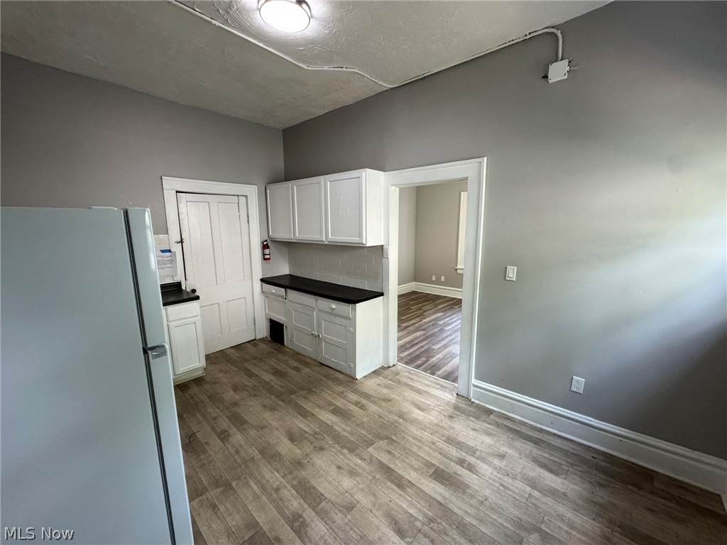 674-676 Carlysle Street Akron, OH 44310 - Photo 11 of 20 Kitchen area featuring wood-finish flooring, white cabinetry, dark countertops, and light gray walls