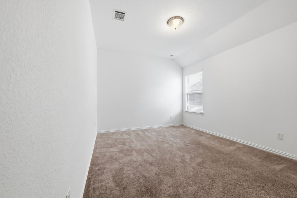 1005 Ridge Runner Drive Georgetown, TX 78628 - Photo 25 of 32 Spacious room with vaulted ceiling, plush carpet flooring, and a window with blinds