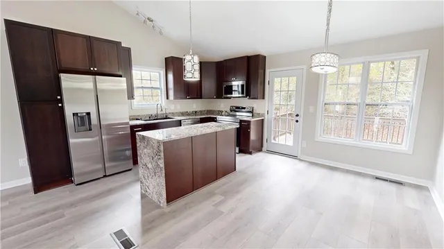 a kitchen with stainless steel appliances granite countertop a stove a sink dishwasher a refrigerator and a oven with wooden floor