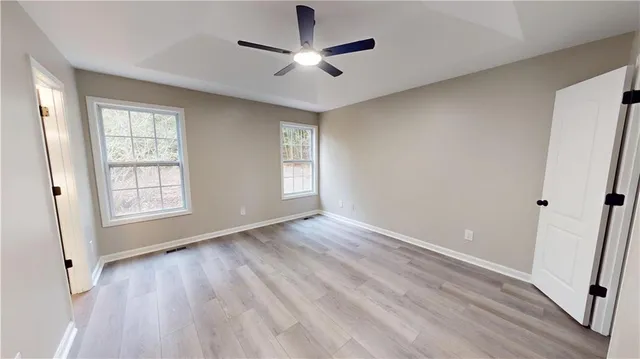 a view of empty room with wooden floor and fan