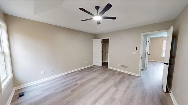 an empty room with wooden floor and a ceiling fan